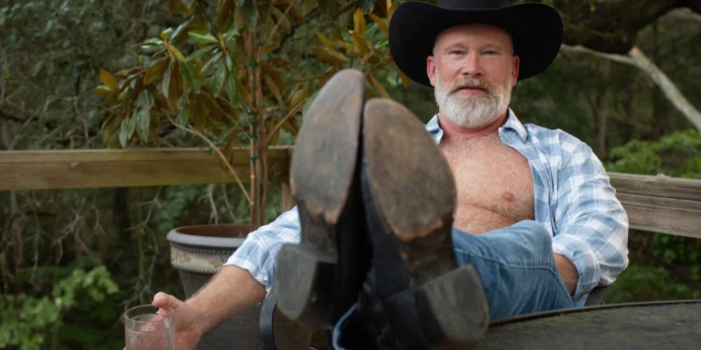 Sexy, furry guy drinking bourbon outdoors.