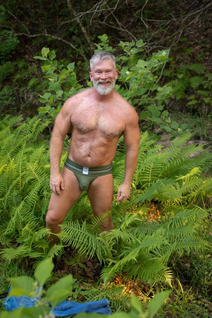 Furry guy wearing a jockstrap in the woods.