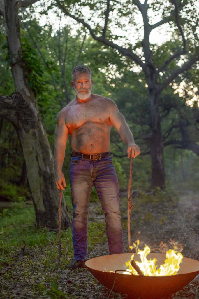 Sexy man by a campfire in jeans.